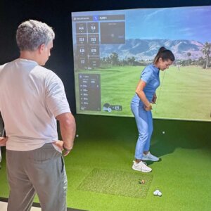 Principiante recibiendo una clase de golf en un simulador indoor en Barcelona
